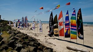 Ein Strand mit mehreren Surfbrettern und Flaggen.