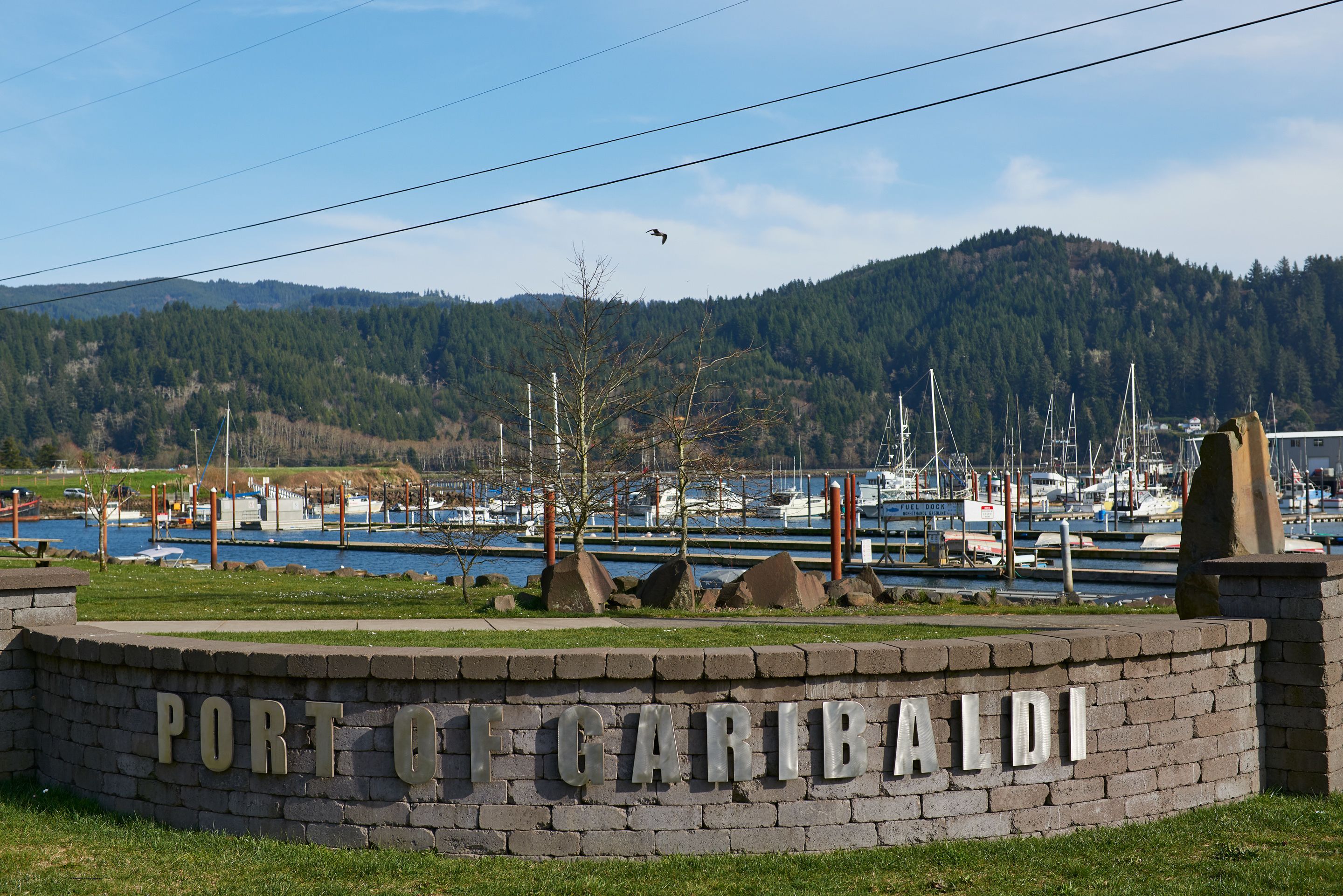 Un panneau indiquant « Port de Caribald », avec un port de plaisance et des bateaux en arrière-plan.
