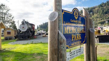 Señal del Parque y Museo Memorial Garibaldi Lions Lumbermens & Railroaders, con una locomotora de vapor al fondo.