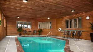 Ein Hallenbad mit Holzwänden und -decke, umgeben von Stühlen und Topfpflanzen.