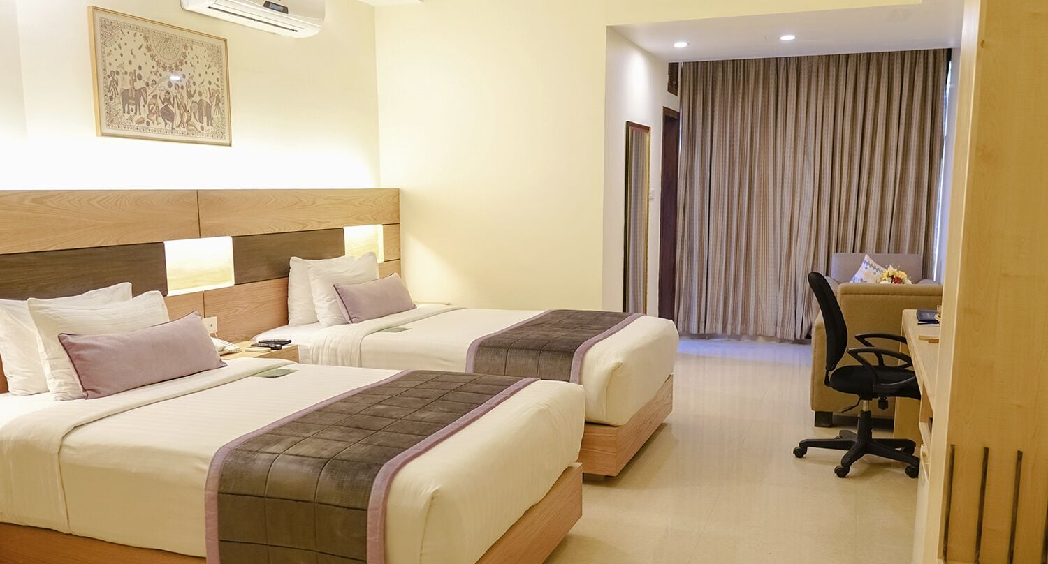 Une chambre d’hôtel avec deux lits, un bureau et une chaise.