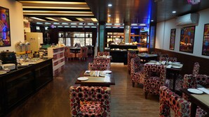Un ristorante con sedie decorate, tavoli in legno e un'area buffet.