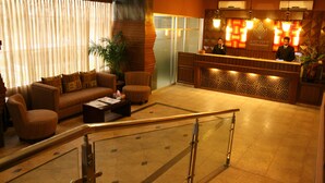 Hall d'albergo con reception, area salotto e scale.
