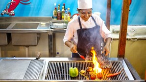 Uno chef cucina alla griglia in una cucina professionale.