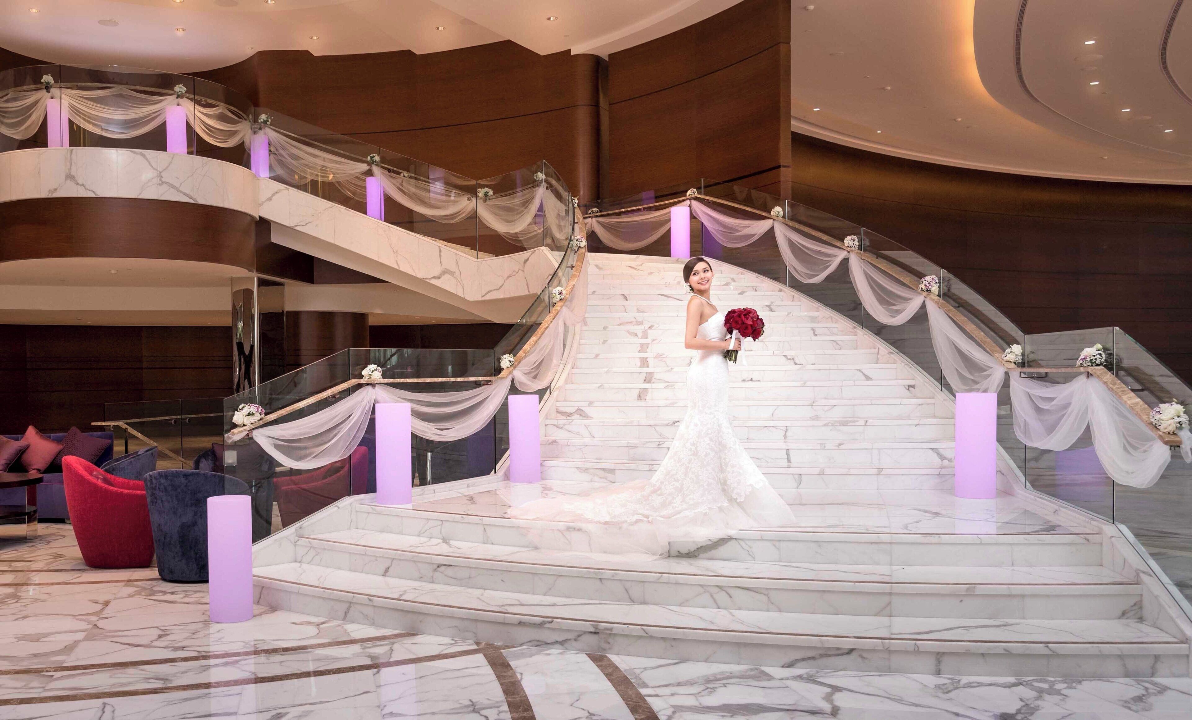 Una majestuosa escalera con escalones de mármol y adornos de tela, que conduce a un nivel superior.