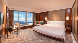 A spacious hotel room with a large bed, a desk, and a chair. There is a large window offering a city view. - Crowne Plaza Macau by IHG (Macau)