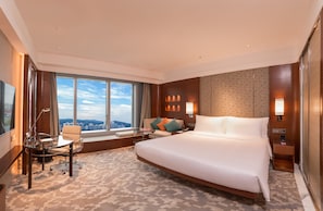 A spacious hotel room with a large bed, a desk, and a chair. There is a large window offering a city view. - Crowne Plaza Macau by IHG (Macau)
