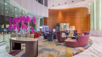 A modern lobby with a central seating area, a glass wall, and a wooden accent wall.