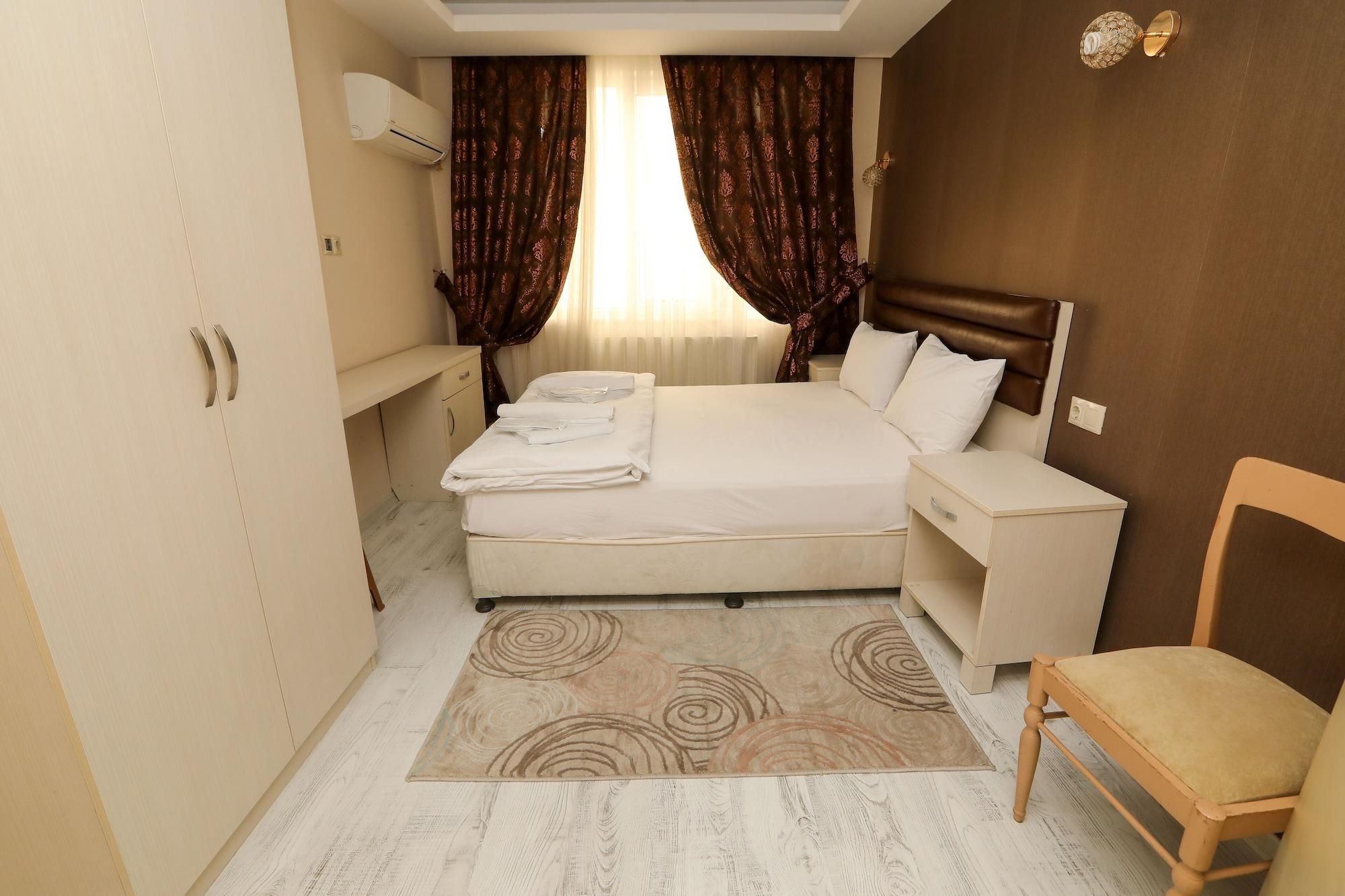 A hotel room with a bed, bedside table, chair, and a small desk.
