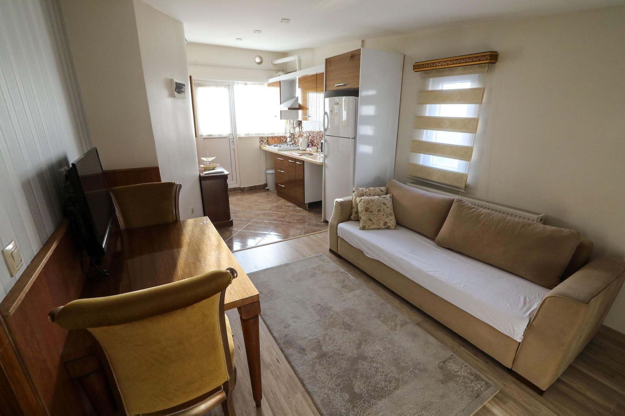 Un espace de vie compact comprenant un canapé, une table à manger, un téléviseur et un coin cuisine.