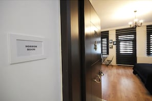 A room with a sign reading 'HORROR ROOM,' wooden flooring, a bed, a small table, and a chandelier. - Suite Dreams Istanbul (Istanbul)