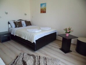 Ein Schlafzimmer mit einem Bett, Nachttischen, einem Teppich und einem kleinen Tisch mit einer Pflanze.