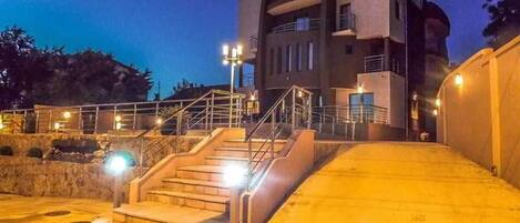 A building with a staircase leading to an entrance, a sign above the entrance, and a well-lit area around the stairs.