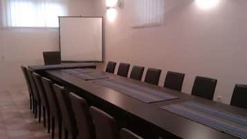 A conference room with a long table, chairs, a projector screen, and a whiteboard.