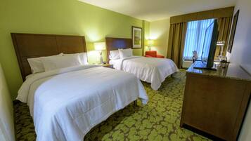 Une chambre d’hôtel avec deux lits, un bureau, une chaise et un téléviseur.