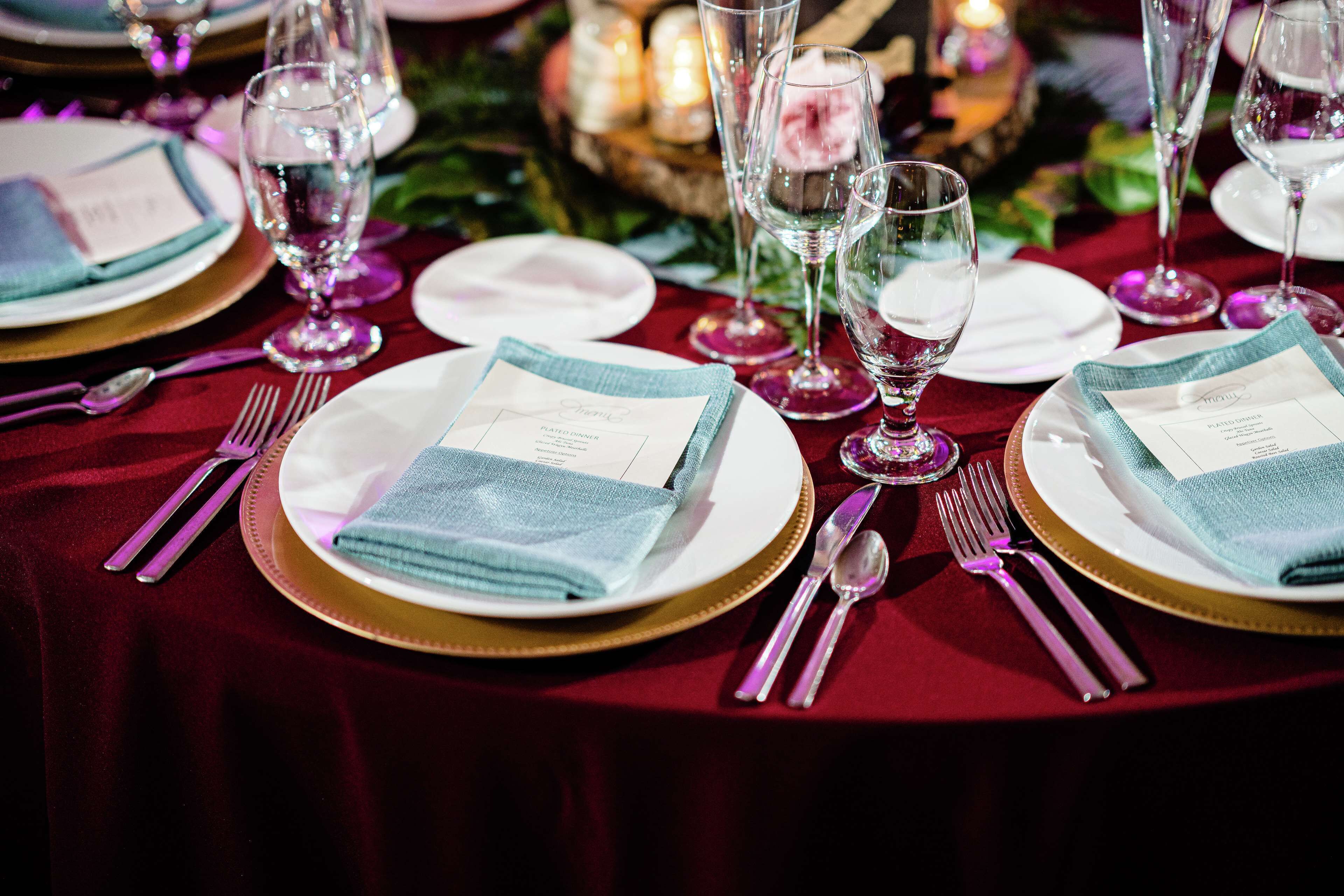 A table set for a formal dinner with white plates, gold chargers, and clear glassware.