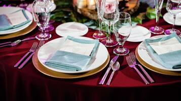 A table set for a formal dinner with white plates, gold chargers, and clear glassware.