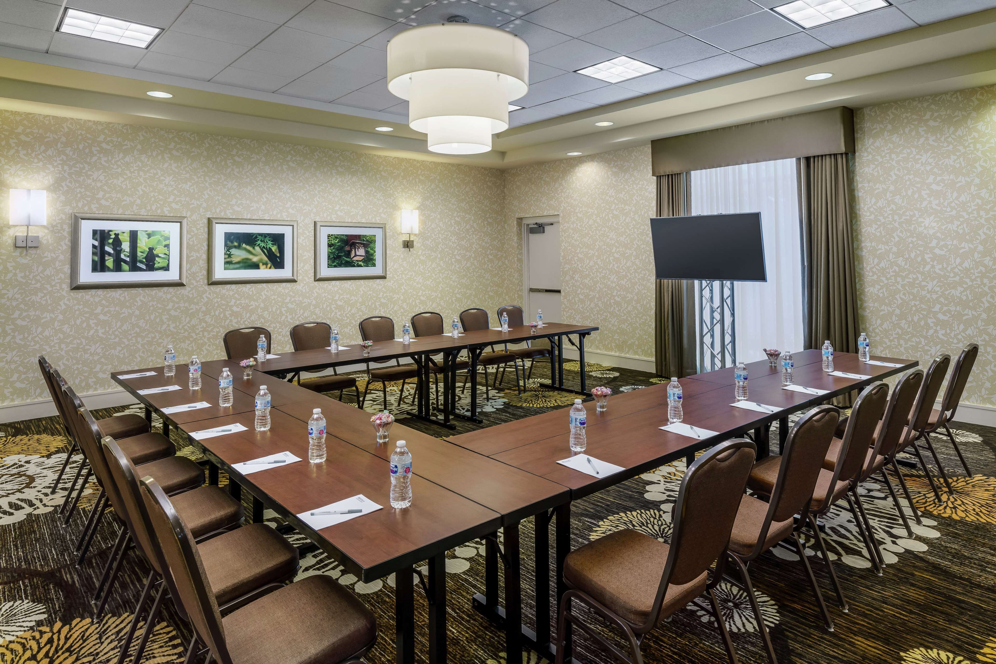 A conference room with a long table, chairs, water bottles, and framed pictures on the wall.