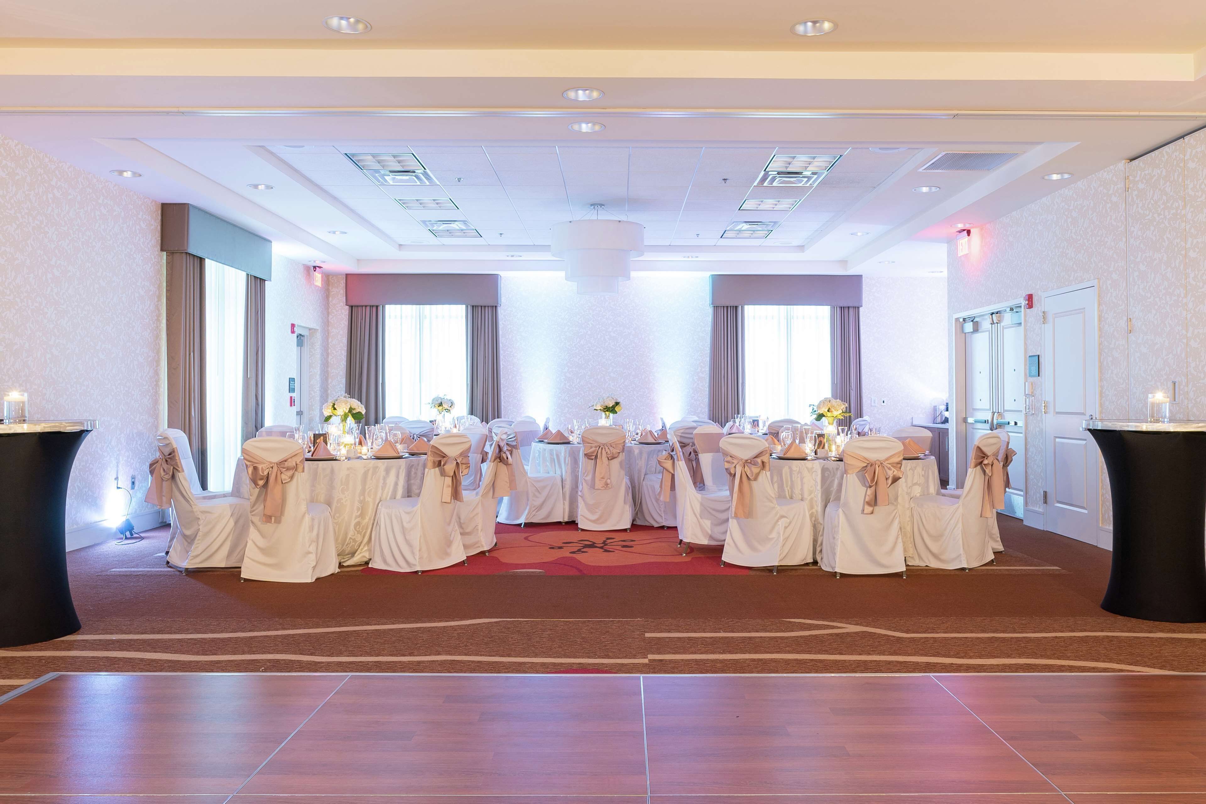 Un salón de banquetes con mesas redondas, sillas y una columna central.