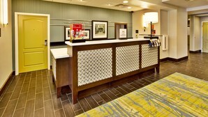 A reception area with a wooden reception desk, a yellow door, and framed pictures on the wall. - Hampton Inn Niagara Falls/Blvd (Niagara Falls)