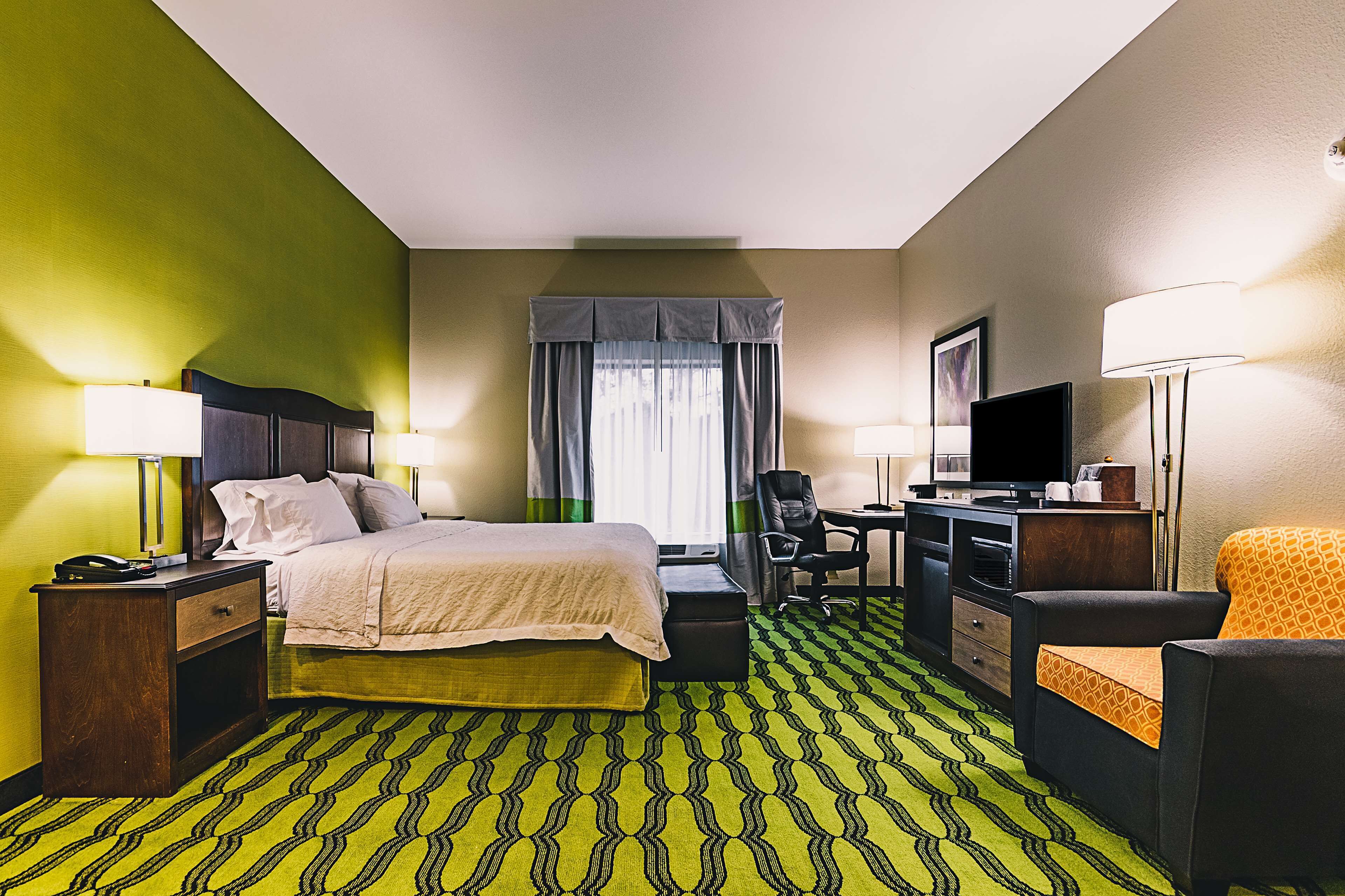 Una habitación de hotel con cama, escritorio, silla y televisor.
