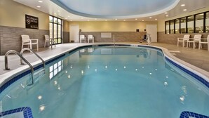 An indoor swimming pool with clear blue water, surrounded by white chairs and a tiled deck. - Hampton Inn Niagara Falls/Blvd (Niagara Falls)