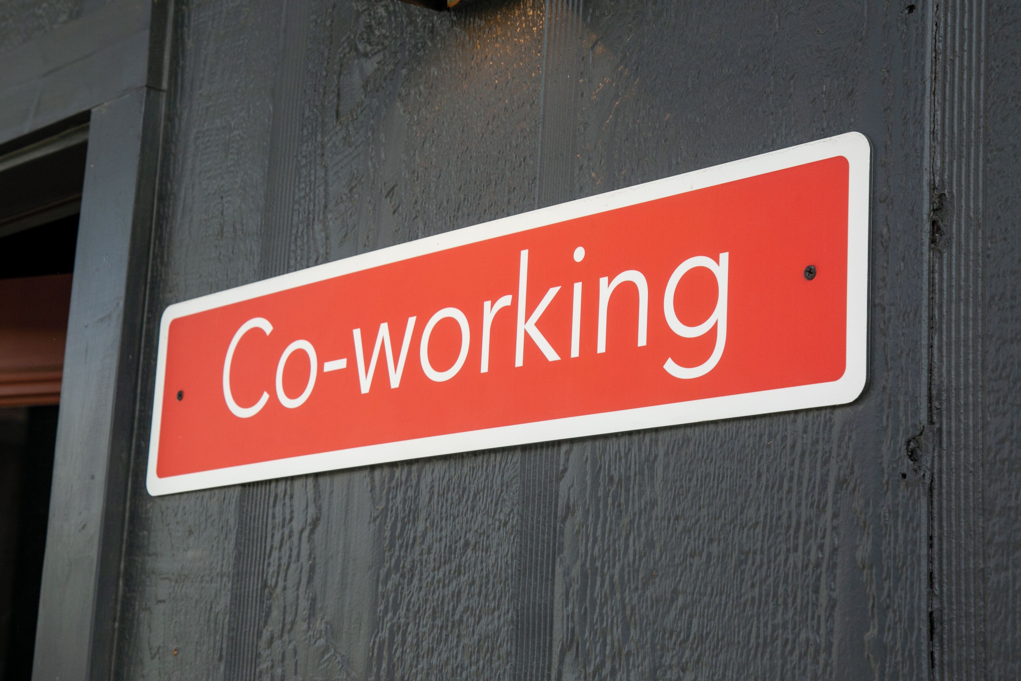 A red sign with white text on a grey wall.