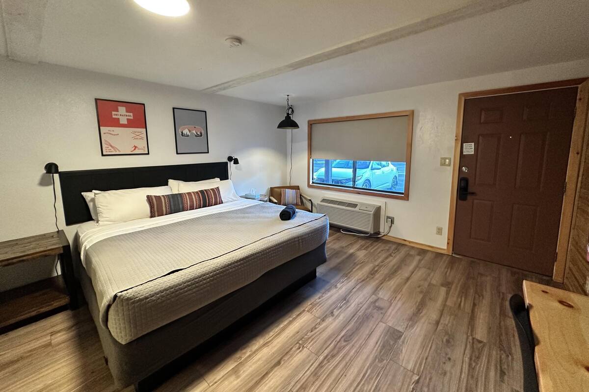 A bedroom with a bed, a window with a view, a heater, and a door.