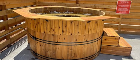 Tinaja de madera con un letrero de advertencia, rodeada por una valla de madera.