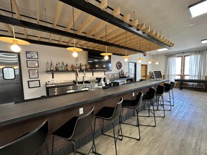 A bar area with a long counter, multiple bar stools, a television, and a chalkboard menu. - Wolf Creek Lodge, BW Signature Collection (South Fork)
