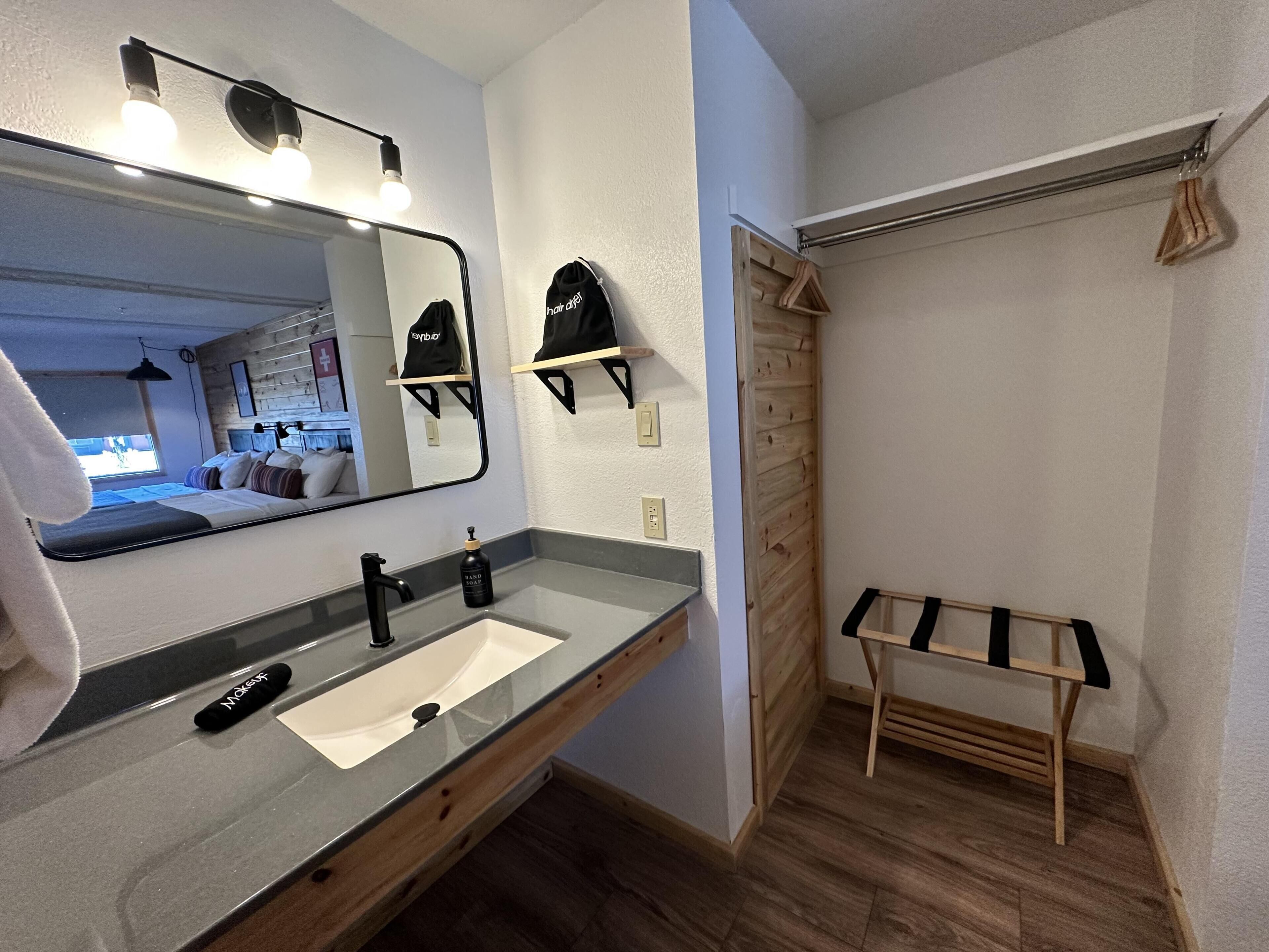 Une salle de bain avec un miroir, un lavabo, une serviette et une étagère en bois.