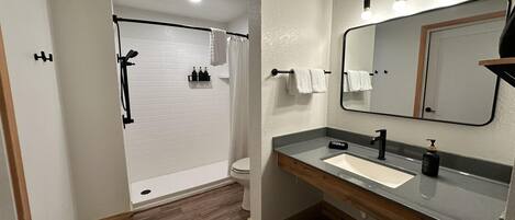 Un baño con ducha, inodoro, tocador con espejo y un perchero para toallas.