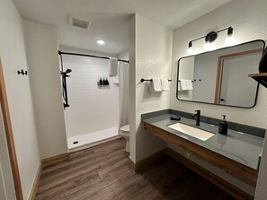 A modern bathroom with a shower, toilet, vanity, and a large mirror. - Wolf Creek Lodge, BW Signature Collection (South Fork)