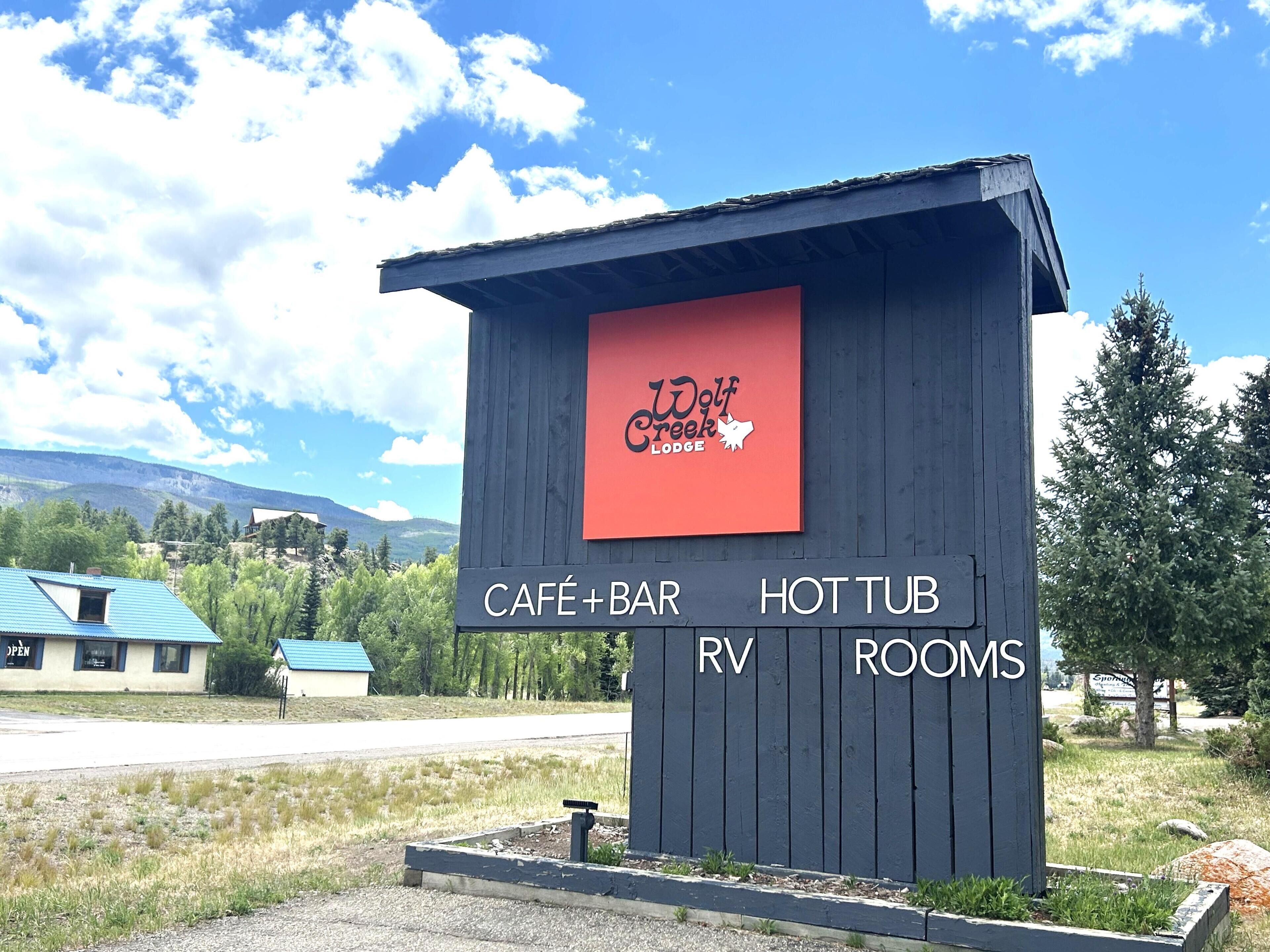 Segnale per Wolf Creek Lodge con servizi che includono un caffè, un bar, una vasca idromassaggio, camere per camper e un'area parcheggio.