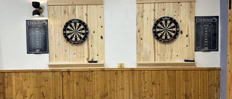 Two dartboards mounted on wooden panels with scoreboards beside them.