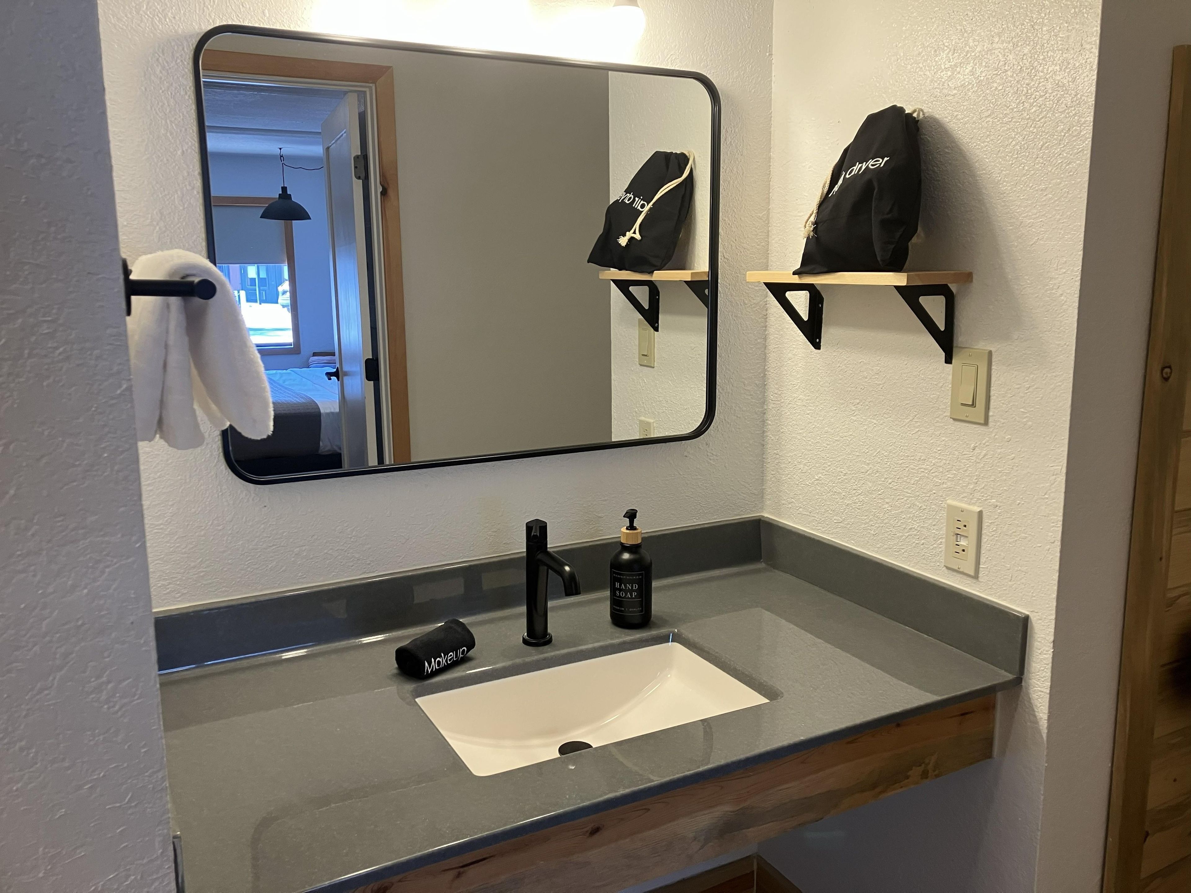 A bathroom with a mirror, a sink, and a towel rack.