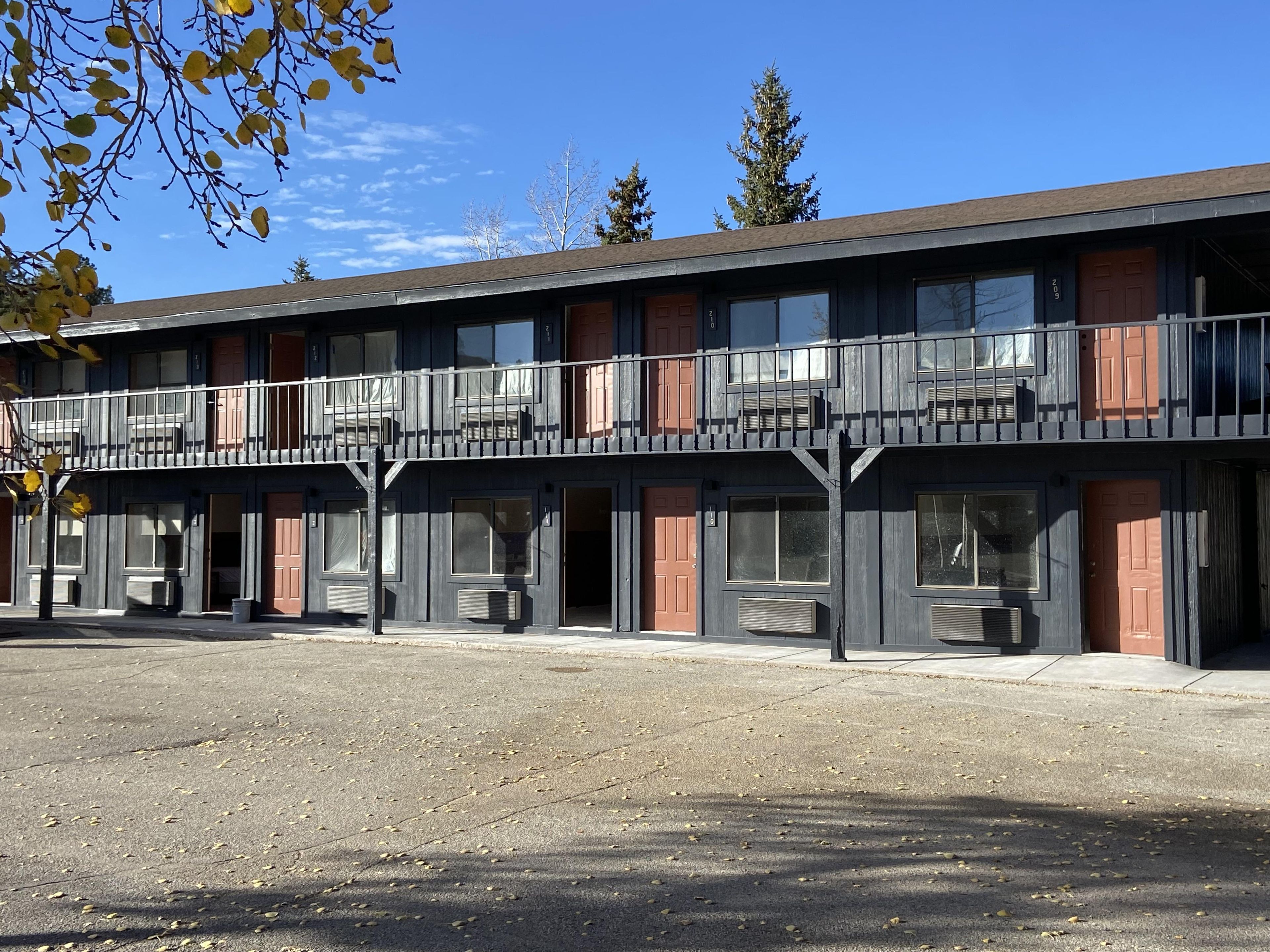 A multi-story motel with balconies, large windows, and a parking lot.