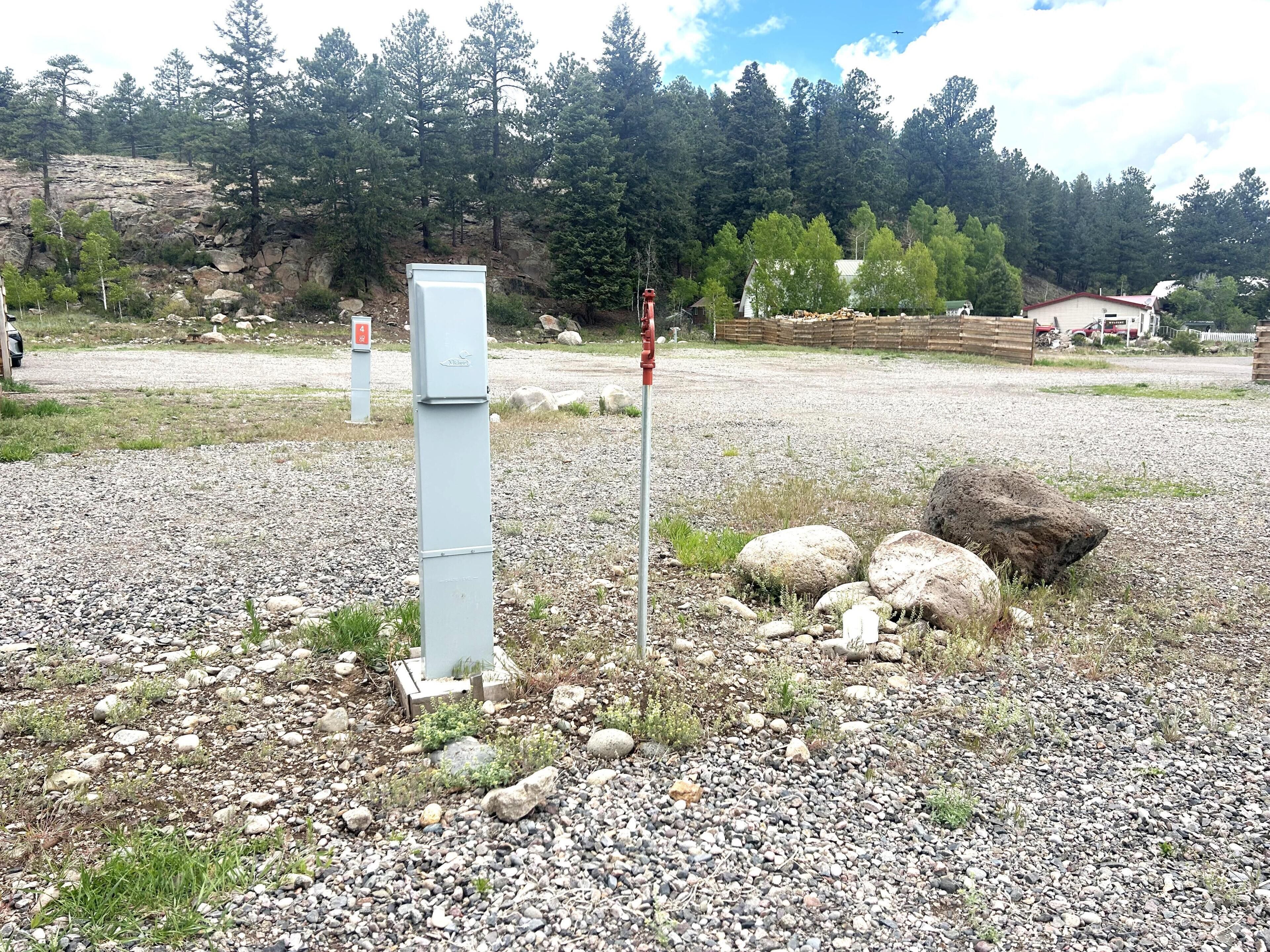 A gravel area with a utility box, rocks, and sparse vegetation.