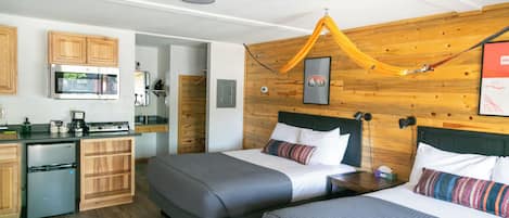 Une chambre d’hôtel moderne avec deux lits, une kitchenette et un mur en bois.