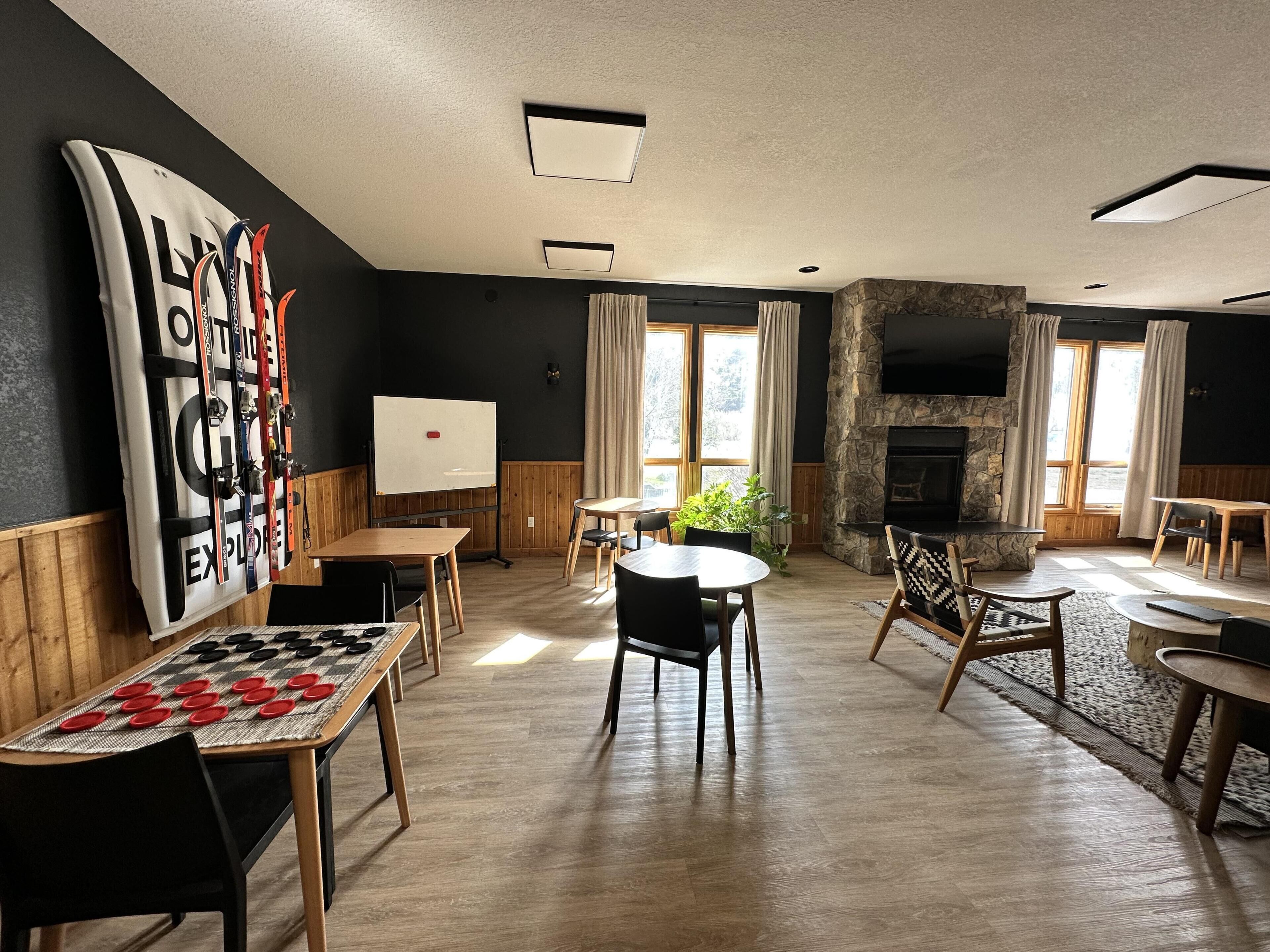 Una habitación con muebles de madera, una pizarra, una chimenea y un ventanal con cortinas.