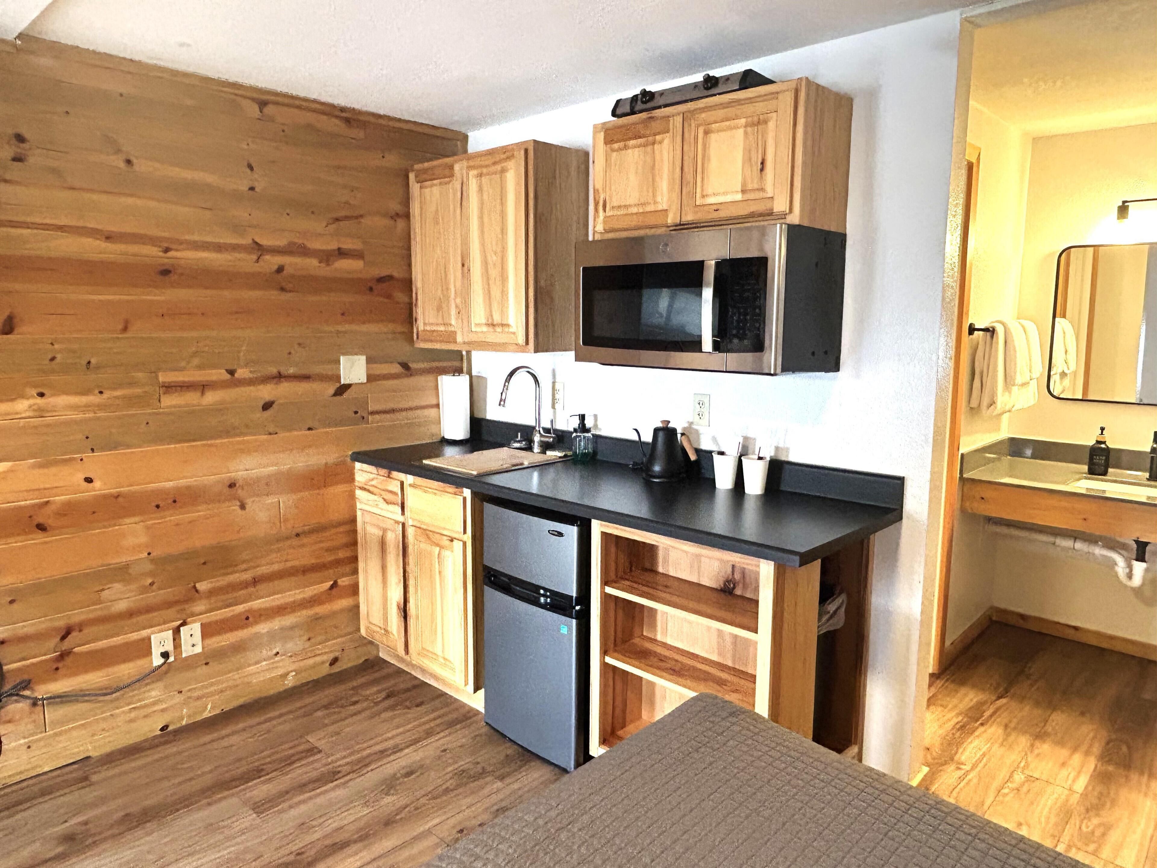 A kitchen with wooden walls, a black countertop, stainless steel appliances, and wooden cabinets.