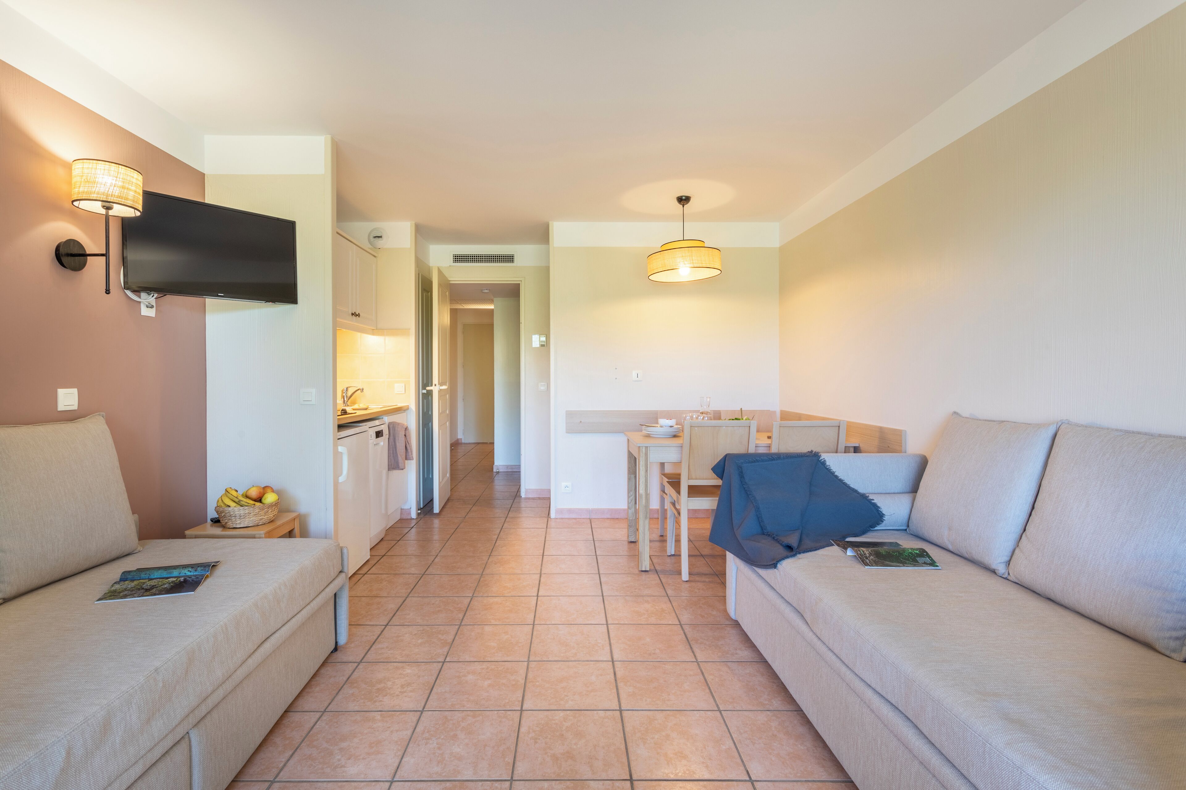 Una sala de estar moderna con un sofá, una mesa de comedor y un televisor montado en la pared.