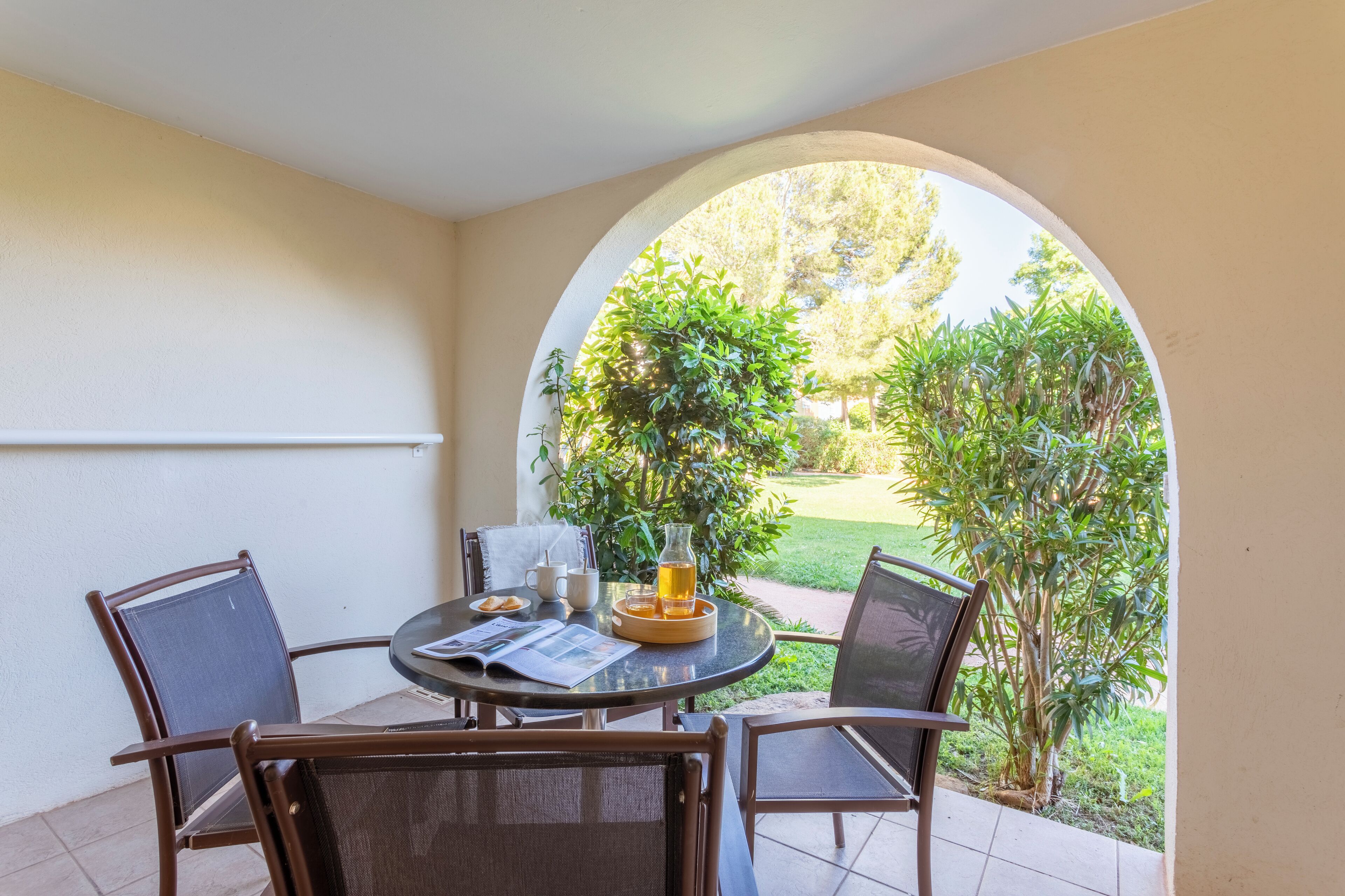 A round table with four chairs, a glass pitcher, a mug, and a tray with snacks.