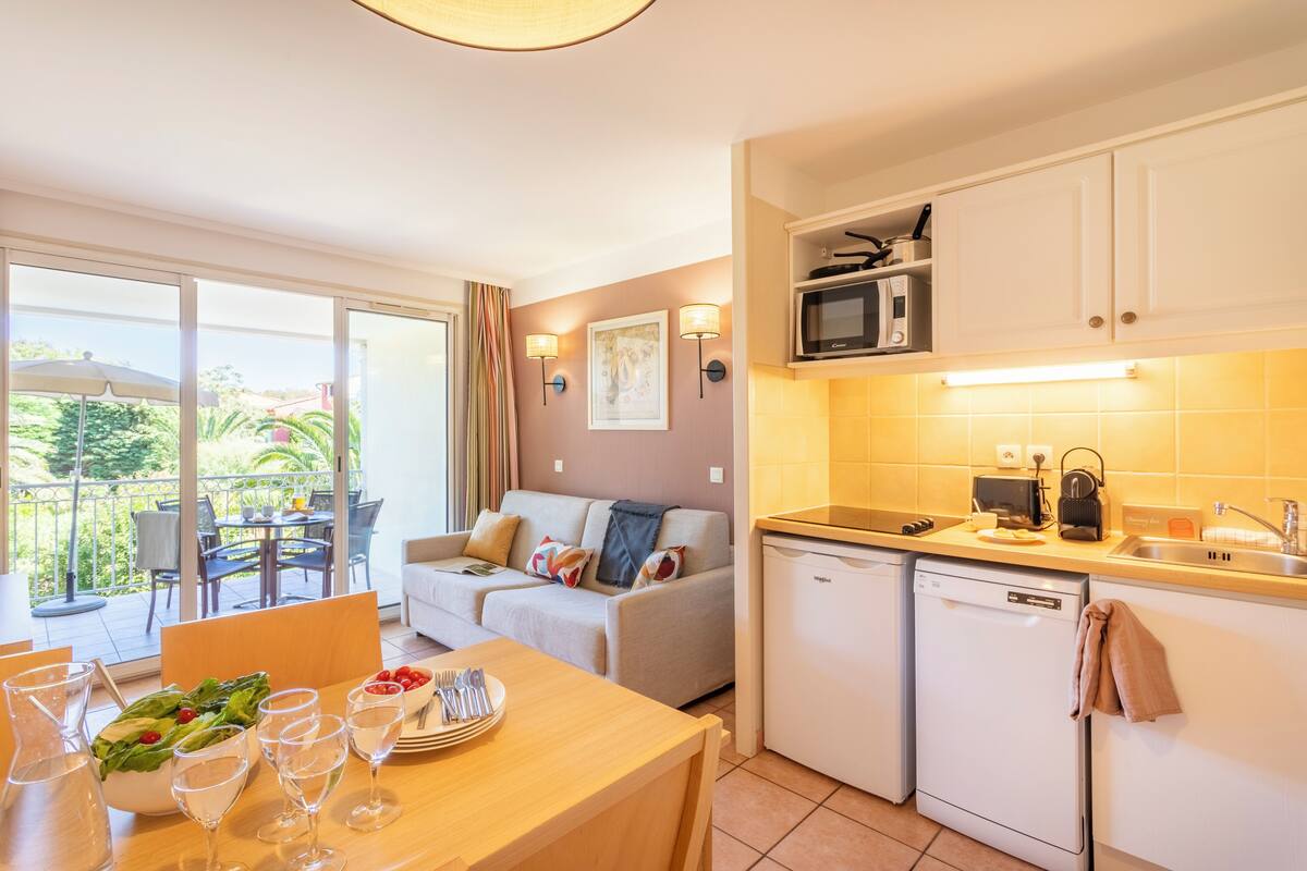 A modern kitchen with a dishwasher, microwave, and a dining area with a table set for two.