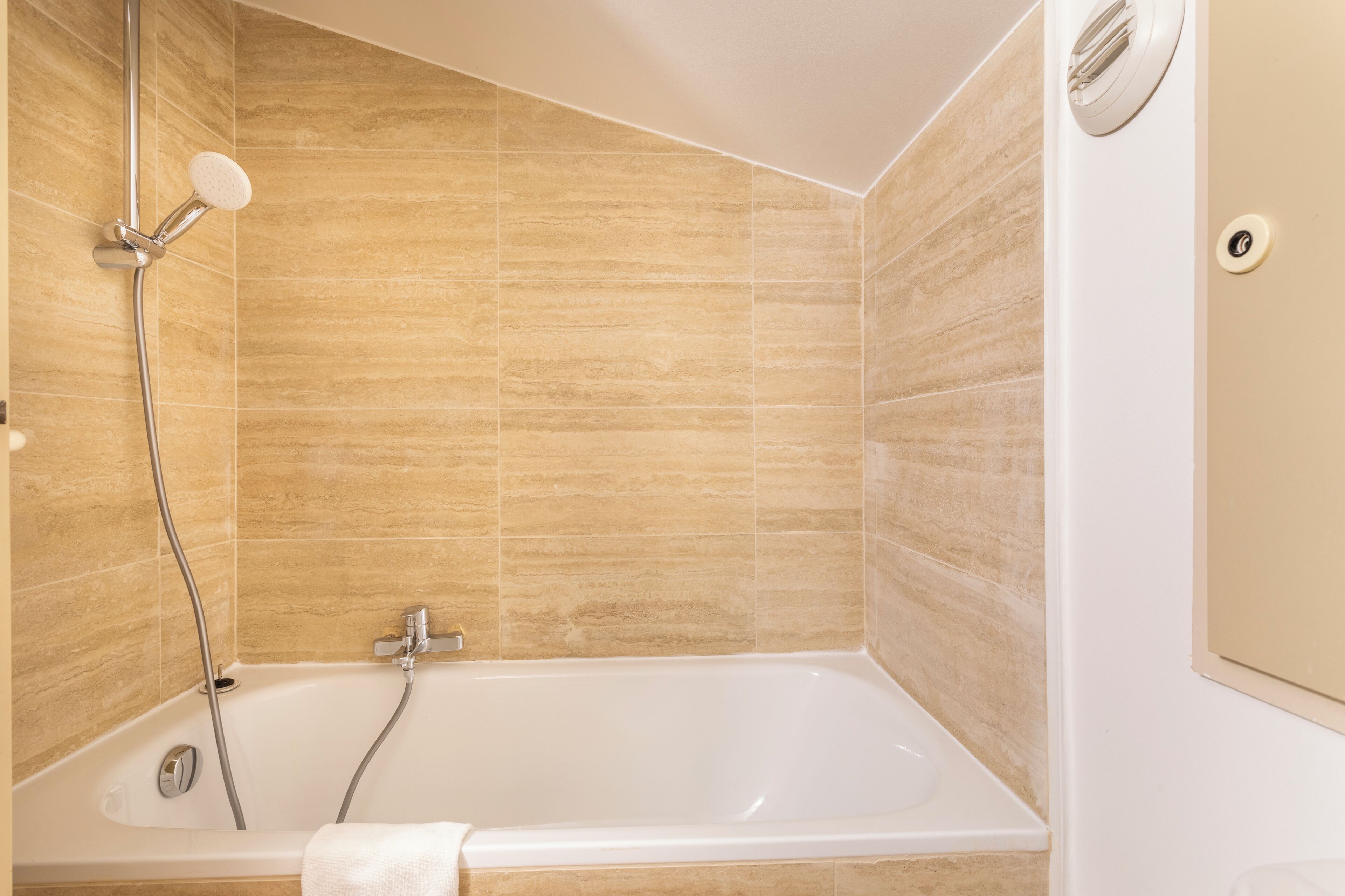 A modern bathroom with a freestanding bathtub, a handheld showerhead, and a wall-mounted control panel.