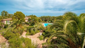 Een tropisch resort met een zwembad, palmbomen en huizen op de achtergrond.