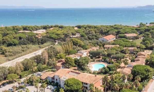 An aerial view of a coastal residential area with houses, a swimming pool, and a road. - Résidence Pierre & Vacances Le Hameau de la Pinède (Hyères)