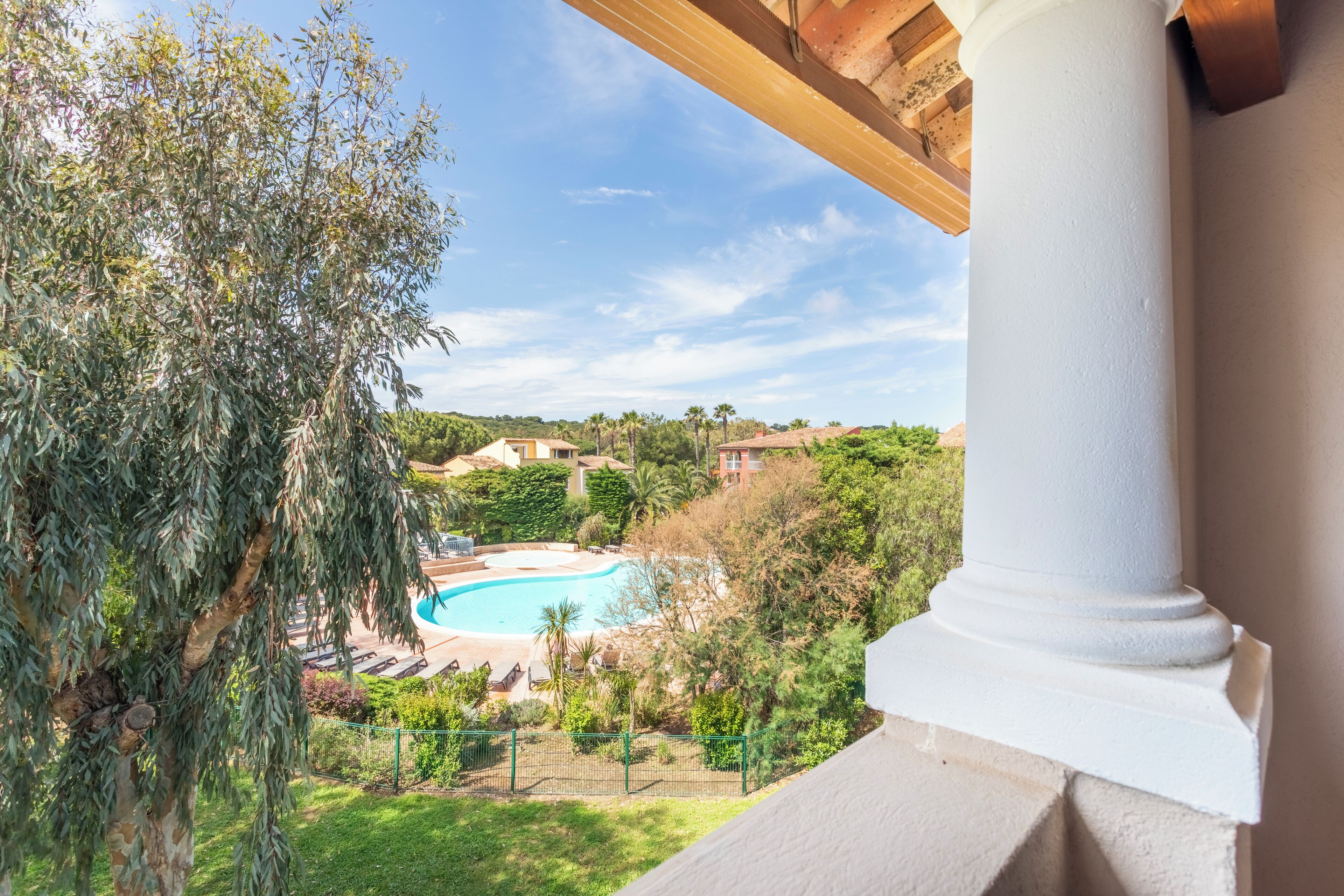 Vista de uma piscina rodeada por vegetação e edifícios.
