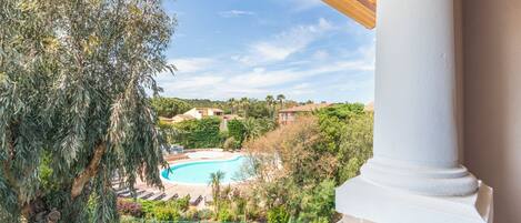 Vista de uma piscina rodeada por vegetação e edifícios.