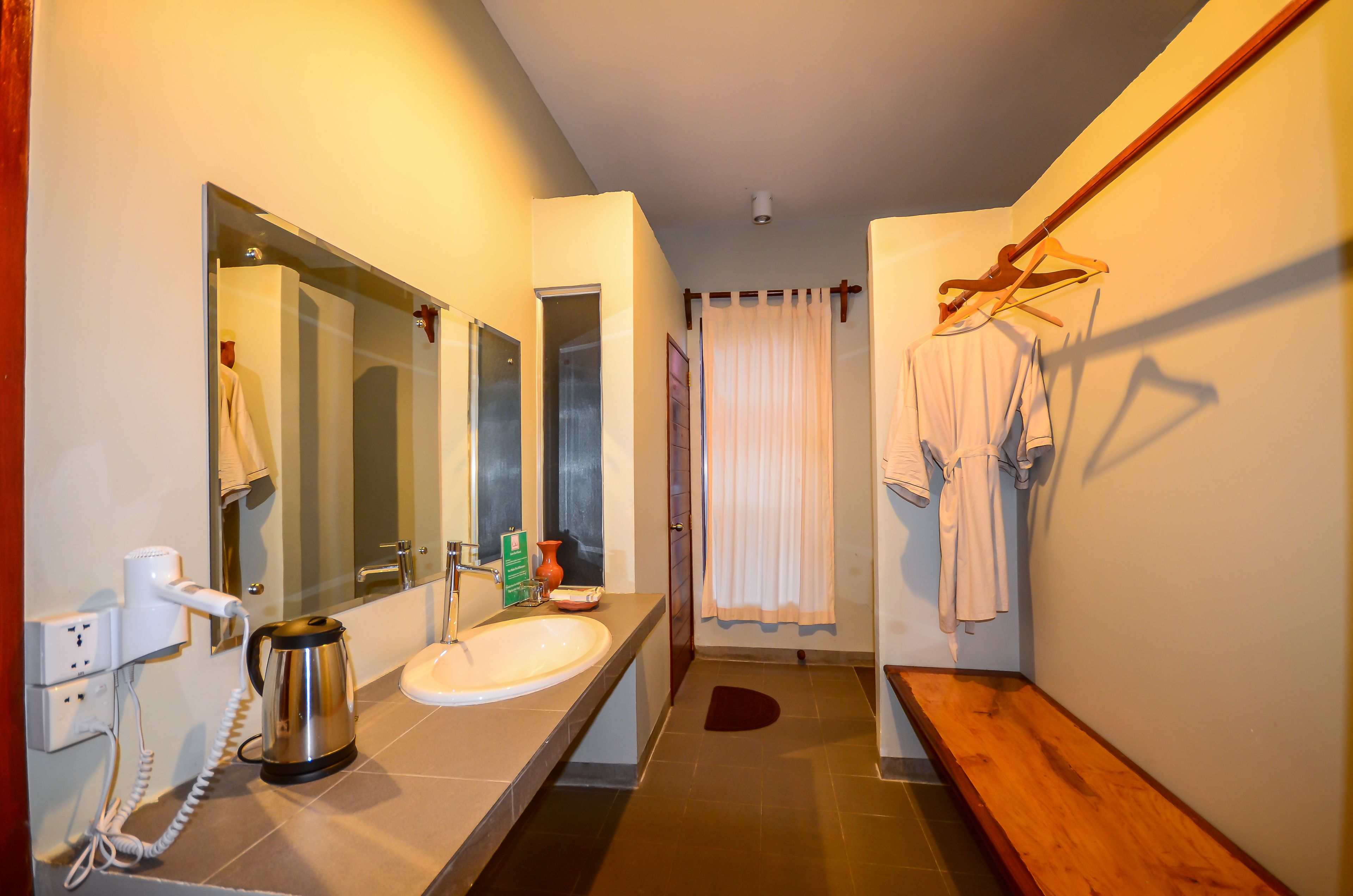 A modern bathroom with a large mirror, a sink, a towel rack, and a bench.